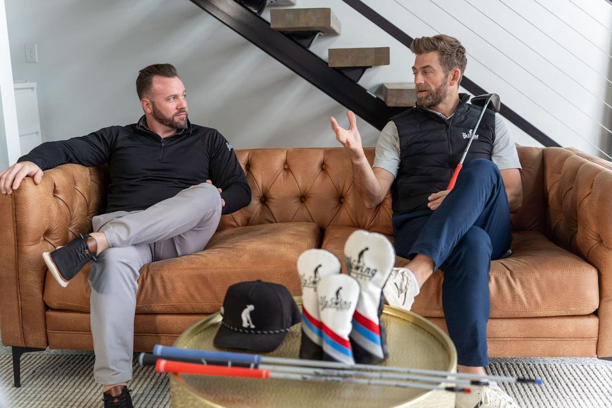UpSwing Golf’s founders talking on a couch beside UpSwing clubs and headcovers